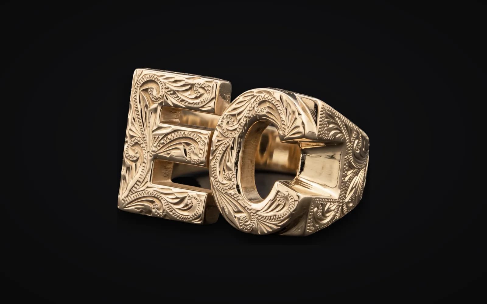 A custom gold ring of the letters E and C, cut out and hand-engraved